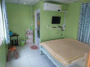 a bedroom with a bed and a tv on the wall at Lovely Farm in Khao Kho