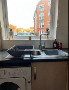 eine Küchentheke mit einem Waschbecken und einem Fenster in der Unterkunft Cozy 2bed apartment w/ parking in Swindon