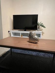 einen Tisch mit einem Fernseher und einer Vase darüber in der Unterkunft Cozy 2bed apartment w/ parking in Swindon