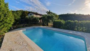 une grande piscine bleue devant une maison dans l'établissement La Bandita Cottage, à San Venanzo