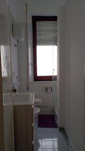 uma casa de banho com um lavatório, um WC e uma janela. em Vela Latina em Soverato Marina