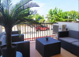 une terrasse avec un palmier, un canapé et une table dans l'établissement Coqueto apartamento a un minuto de Cala Blanca, à Cala Blanca