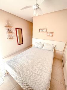 1 dormitorio con 1 cama blanca y ventilador de techo en Apt na Praia do Morro,2 quadras do mar,com Garagem, en Guarapari