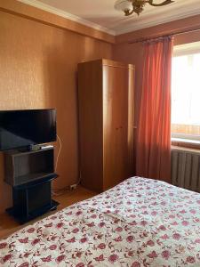 a bedroom with a bed and a flat screen tv at Plaza City Apartments in Kyiv