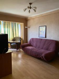 キーウにあるPlaza City Apartmentsの紫色のソファとテーブル付きのリビングルーム