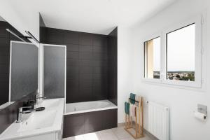 a bathroom with a sink and a bath tub at Maison neuve au centre-ville proche de l'aéroport in Guipavas