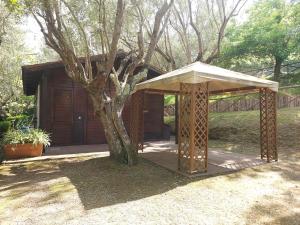 una estructura de madera con un árbol frente a una casa en CHALET con spiaggia privata, en Bracciano