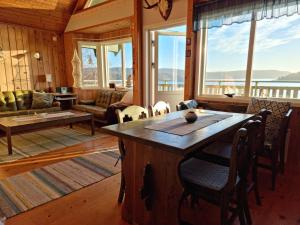 una sala de estar con una gran mesa de madera y ventanas en Sandy Beach Cottage, en Uddevalla