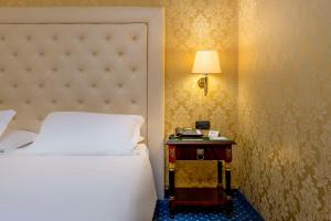 a bedroom with a bed and a table with a lamp at Best Western Cavalieri Della Corona in Cardano al Campo