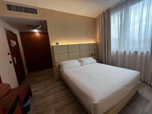 Un dormitorio con una gran cama blanca y una ventana en Best Western Cavalieri Della Corona en Cardano al Campo