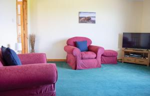 uma sala de estar com duas cadeiras e uma televisão em Tulm Bay em Kilmaluag