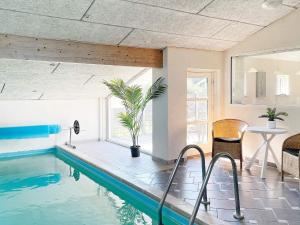 a swimming pool in a house with a table and chairs at 12 person holiday home in V ggerl se in Marielyst