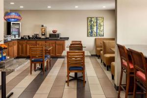 a restaurant with wooden chairs and a table and a counter at Baymont by Wyndham Cedar Rapids in Cedar Rapids