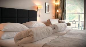 a large white bed with pillows on top of it at Havila Hotel Geiranger in Geiranger