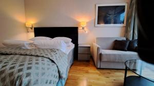 a bedroom with a bed and a couch and a chair at Havila Hotel Geiranger in Geiranger