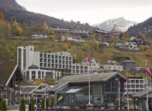 a town with a large building on a mountain at Havila Hotel Geiranger in Geiranger