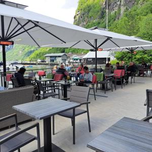 a group of people sitting at tables with umbrellas at Havila Hotel Geiranger in Geiranger