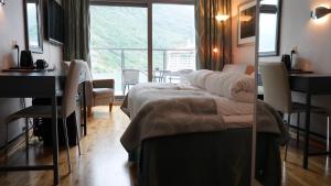 a bedroom with a bed and a desk and a window at Havila Hotel Geiranger in Geiranger