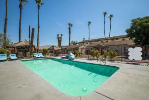 a swimming pool in a parking lot with palm trees at Rodeway Inn near Coachella in Indio
