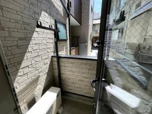 ein Badezimmer mit zwei Waschbecken und einer Ziegelwand in der Unterkunft Ferio Kita-ikebukuro Apartment 103 in Tokio