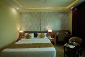 a hotel room with a large bed and a desk at The Royal Bihar in Patna