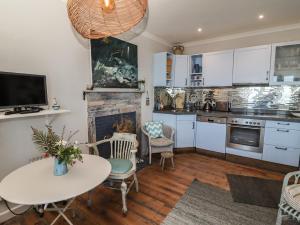 a kitchen with white cabinets and a table and chairs at Starfish in Penzance