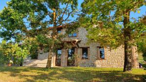 une maison en pierre avec des arbres devant elle dans l'établissement La Bandita Cottage, à San Venanzo