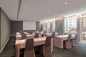 a conference room with tables and chairs and a screen at TRYP by Wyndham New Taipei Linkou 新北林口爵怡溫德姆酒店機場捷運MRTA9林口站 in Linkou