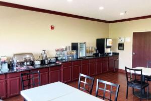 a kitchen with a counter top with chairs and tables at AmericInn by Wyndham Grinnell in Grinnell