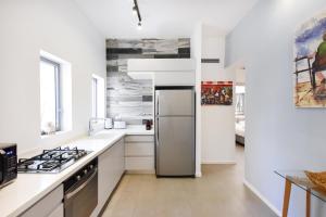 a white kitchen with a stainless steel refrigerator at Magic Lily by HolyGuest in Tel Aviv +13 photos