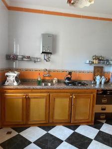 uma cozinha com armários de madeira e piso em azulejo em High quality appartement (4éme étage) em Martil