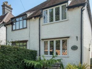a white brick house with windows and a hedge at Pass the Keys Cosy 3 Bed Cottage in Chorleywood in Chorleywood