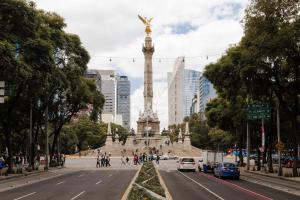 a street in a city with a statue in the distance at Sonder Las Alas in Mexico City