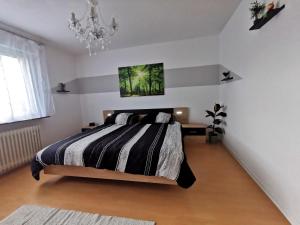 a bedroom with a black and white bed and a chandelier at 3 Zimmer-Apartment mit Terrasse in Gernsbach