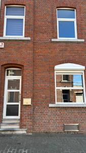 un edificio de ladrillo rojo con 2 ventanas con adornos blancos en Casa Polizzi - Maison entière en Fontaine-lʼÉvêque