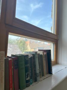 una fila de libros sentados en el alféizar de una ventana en Woodstock Oxford Street- Entire Cosy Apartment- 5 mins to Blenheim Palace en Woodstock