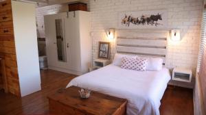 1 dormitorio con 1 cama grande y pared de ladrillo en The Owl House, en Jeffreys Bay