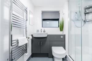 a bathroom with a sink and a toilet at K Suites - Colne House in Lowestoft