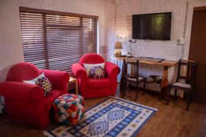 a living room with two red chairs and a television at The Owl House in Jeffreys Bay