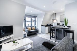 a living room with a couch and a kitchen at K Suites - Colne House in Lowestoft