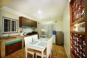 a kitchen with a table and white chairs in it at Green Hill Apartment Kathmandu in Kathmandu