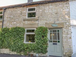 a stone building with a door and a window at Flora Cottage in Buxton