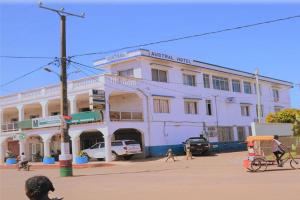 a white building with people walking in front of it at Austral Hotel in Farafangana