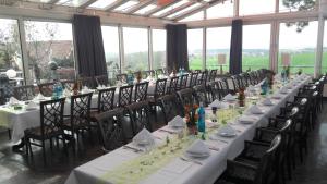 a long table with tables and chairs in a room with windows at Restaurant und Hotel Alter Brunnen 