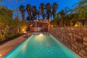 a swimming pool in a backyard with a stone wall at The Hosteller Heritage Palace, Jodhpur in Jodhpur