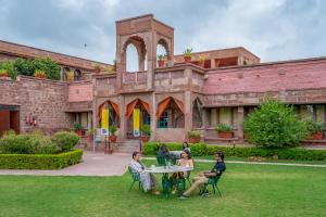 un groupe de personnes assises à une table devant un bâtiment dans l'établissement The Hosteller Heritage Palace, Jodhpur, à Jodhpur