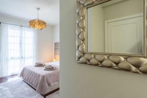 una camera da letto con un letto e uno specchio a parete di VILLA LEONARDO a Caniço