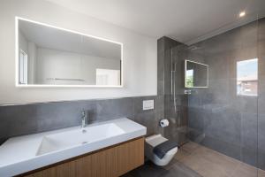 La salle de bains est pourvue d'un lavabo, de toilettes et d'un miroir. dans l'établissement Neubauwohnung mit Lift in Matten, à Matten