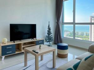 a white living room with a tv and a table at Seaview Private Master Bedroom in a Shared Unit in Tanjong Tokong