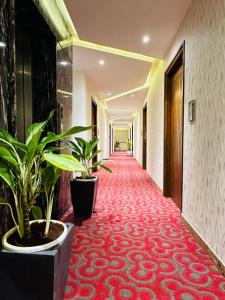 un pasillo de un hotel con plantas y una alfombra roja en ROYAL ACE LUXUR, en Bangalore